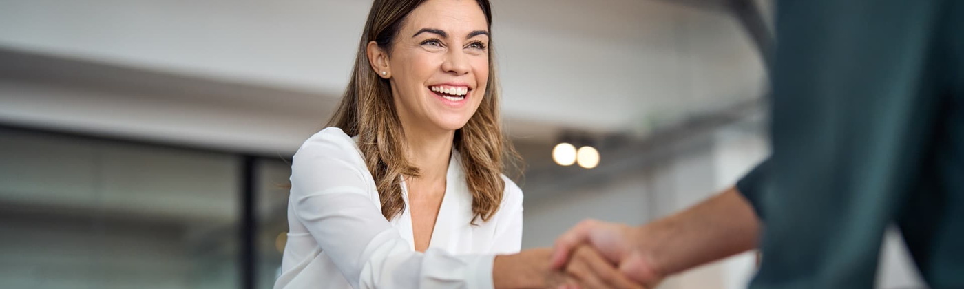 Frau Eine Frau schüttelt einem Mann die Hand in einem modernen Büro